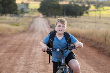 Boy riding bike on remote country lane
