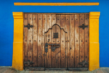 Bogota, Colombia - Closed wooden door with blue-yellow wall