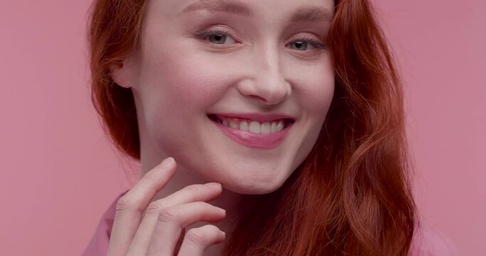 Portrait of Smiling Happy woman looking at Camera and posing in front of Objective. Looking charming and Lovely. Having nice Smile and beautiful Appearance. Attractive model with long Red Hair.