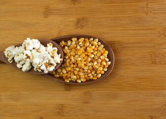 Obraz na płótnie Canvas .Corn and popcorn in wooden spoon in the middle of wooden table