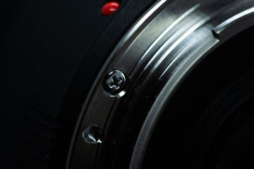 Macro closeup photo of lens to dslr camera on dark background view of red dot and silver extension...