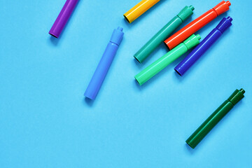 Colorful felt tip pens on blue backdrop. Top view, copy space. Back to school concept.