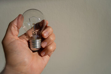 hand holding incandescent lamp, with light background
