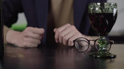 Male Caucasian fingers tapping the table. Hands of unrecognizable nervous man close-up. Unknown guy pounding table with fist. Wineglass standing at front. Stress, nervousness, anxiety.