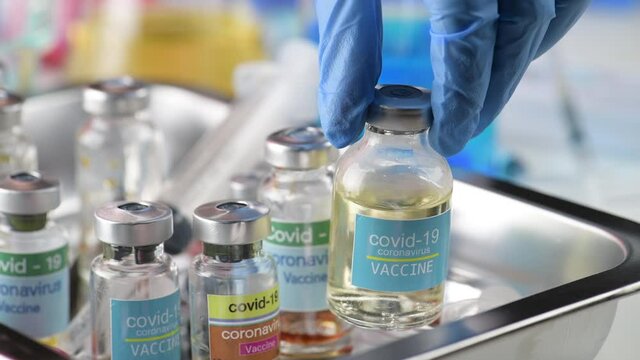 hand of scientist doctor holding vial ampoule bottle human use vaccine syringe injection coronavirus covid19 at hospital lab. Researcher in laboratory Try to extract vaccine for virus covid19 Success.