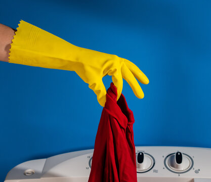 hands with yellow gloves holding a red shirt and blue background