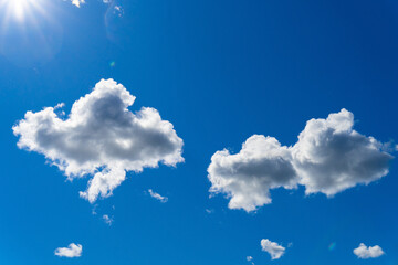 Blue sky with white clean clouds lit by morning sunlight