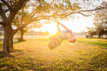 Young caucasion boy playing on backyard tire swing in vibrant afternoon sunlight