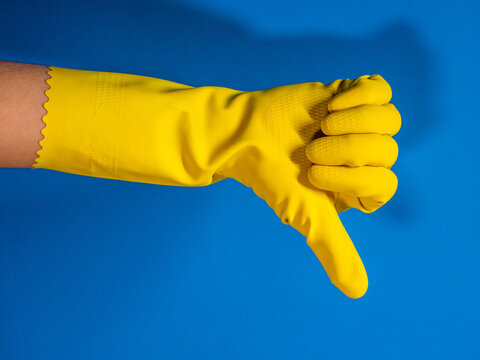 cleaning hand of girl with yellow gloves with thumb down gesture