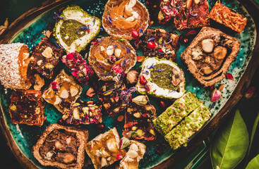 Flat-lay of variety of Turkish traditional lokum sweet delight in plate over green Moroccan tile...