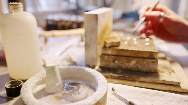 Close up of female jeweller putting solder onto pieces in studio - shot in slow motion 