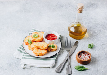 Hash brown or potato pancakes on plate with catsup on light gray background