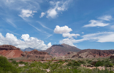 Paisaje arido de montañas y nubes en un dia soleado con cielo azul