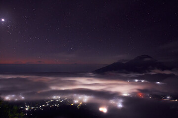 Fototapeta na wymiar Bali indonesian island from the top of Batur mountain at the night time with night star sky and city lights at the bottom