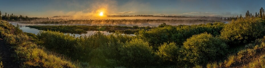 Sunrise over the Madison River just outside Yellowstone National Park with mirror like reflection from the water and steam fog, Baker's Hole Campground, Montana