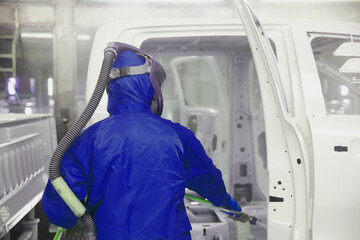 Painter wearing full PPE protector pain vehicle , painting car body process
