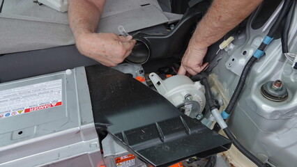 A man's hand pointing to location of hybrid battery fan in 2011 Toyota Prius. 