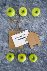 Contactless Delivery text on notepad among apples and with shopping bag and house icon concept of groceries shopping during quarantine or lockdown