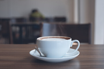 white cup of hot latte coffee on wooden table in coffee shop with nobody