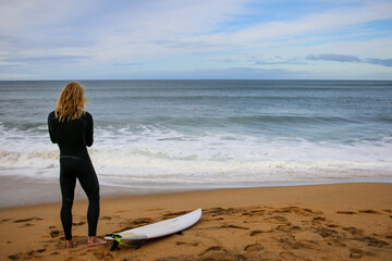 a young blonde surfer preparing himself to join the surf on an early morning surf, coastal Victoria, great ocean road, Australia