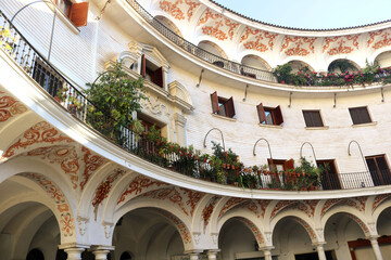 circular building in an andalusian courtyard in Seville, with arches, windows, ornaments, and plants