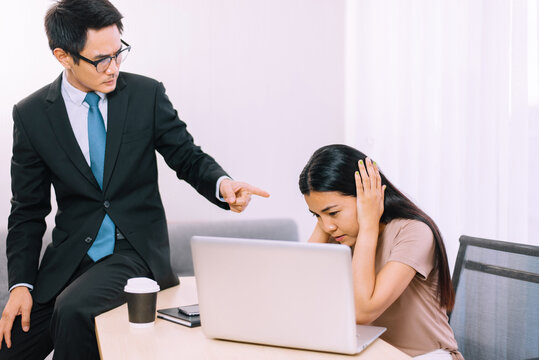 Asian man boss pointing finger to stressed woman employee in office