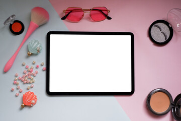 Top view of woman beauty blogger working desk with tablet,cosmetic, pearl, on pink and blue  pastel table. Flat lay background.
