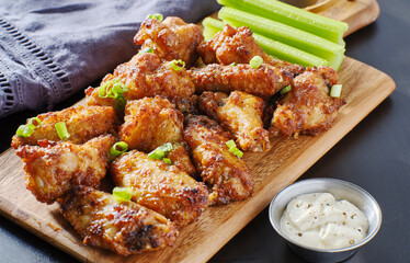 pile of bbq garlic bone-in chicken wings on wooden board