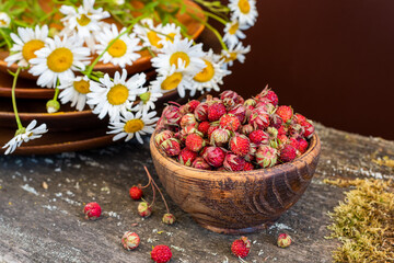 Fototapeta na wymiar Sweet forest strawberries and a bouquet of daisies on a wooden background