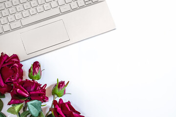 workplace with a gray laptop and flowers on a white background