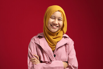 Fototapeta premium Happy smart cute young confident Asian teenage muslim girl smiling at camera with arms crossed