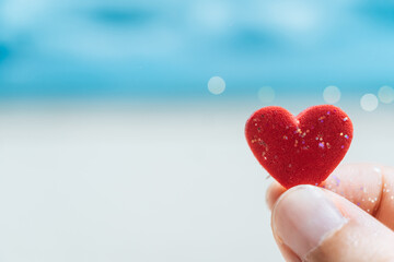 Hand hold little heart meaning feel love with summer beach with blue sky.