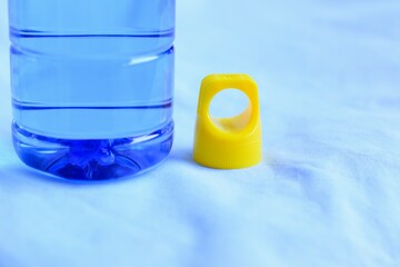 A blue plastic bottle water with yellow bottle cap isolated on blue sky background.