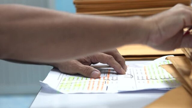 Hand of man for approval or checked the document envelope brown with a red pen.