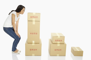 Woman standing beside a stack of cardboard boxes, contemplating