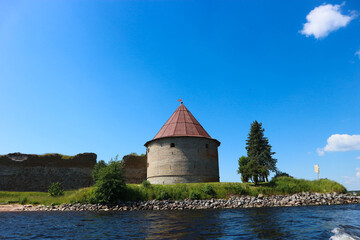 Fototapeta premium Corner tower of medieval Shlisselburg (Oreshek) fortress on the island in the Ladoga lake in Russia against blue sky