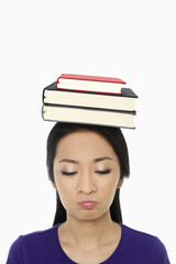 Woman with a stack of books on her head, sulking