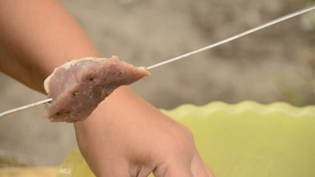 Stringing meat on a skewer closeup