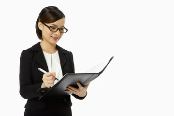 Businesswoman writing notes in folder