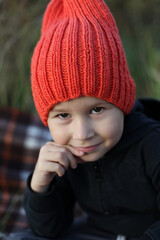 Portrait of a little boy in a red knitted hat