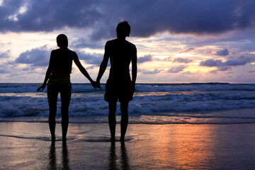 Couple in love walking along the seashore at sunset