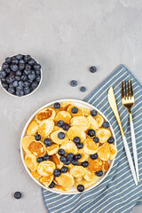Trendy home breakfast with tiny pancakes and blueberry on gray concrete background. Flat lay, top view, overhead, mockup, template, copy space. View from above