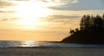 cloudy beach coastal silhouette against morning sun.