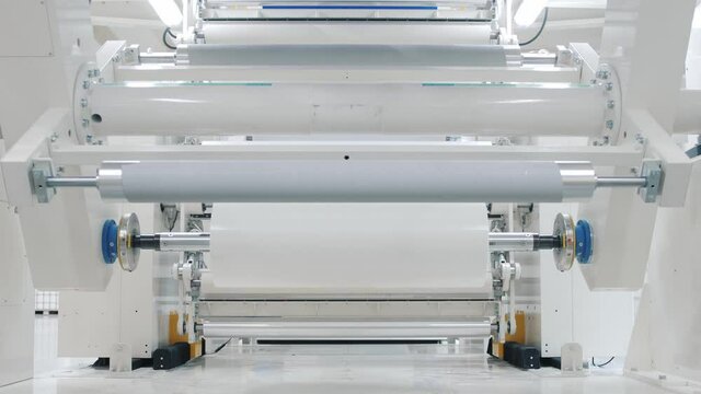 automated production line operates with white adhesive tape strip in brightly lit plant workshop closeup