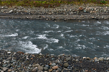 nature and travel concept - river water flow and stones