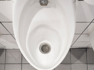 Fototapeta premium White ceramic urinal chamber pot with male public hair. Male hair lost problem.