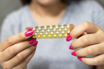 Woman is holding birth control pills to prevent pregnancy