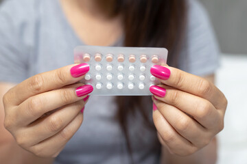 Woman is holding birth control pills to prevent pregnancy, focus hands