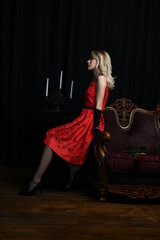 young and beautiful girl in a red dress in a romantic style with a candelabrum