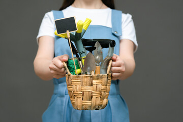 Gardener is holding in hands a bucket with garden tools close up.
